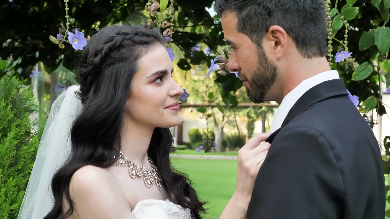 Un couple de mariés partage un regard sous une arche fleurie, image d’illustration